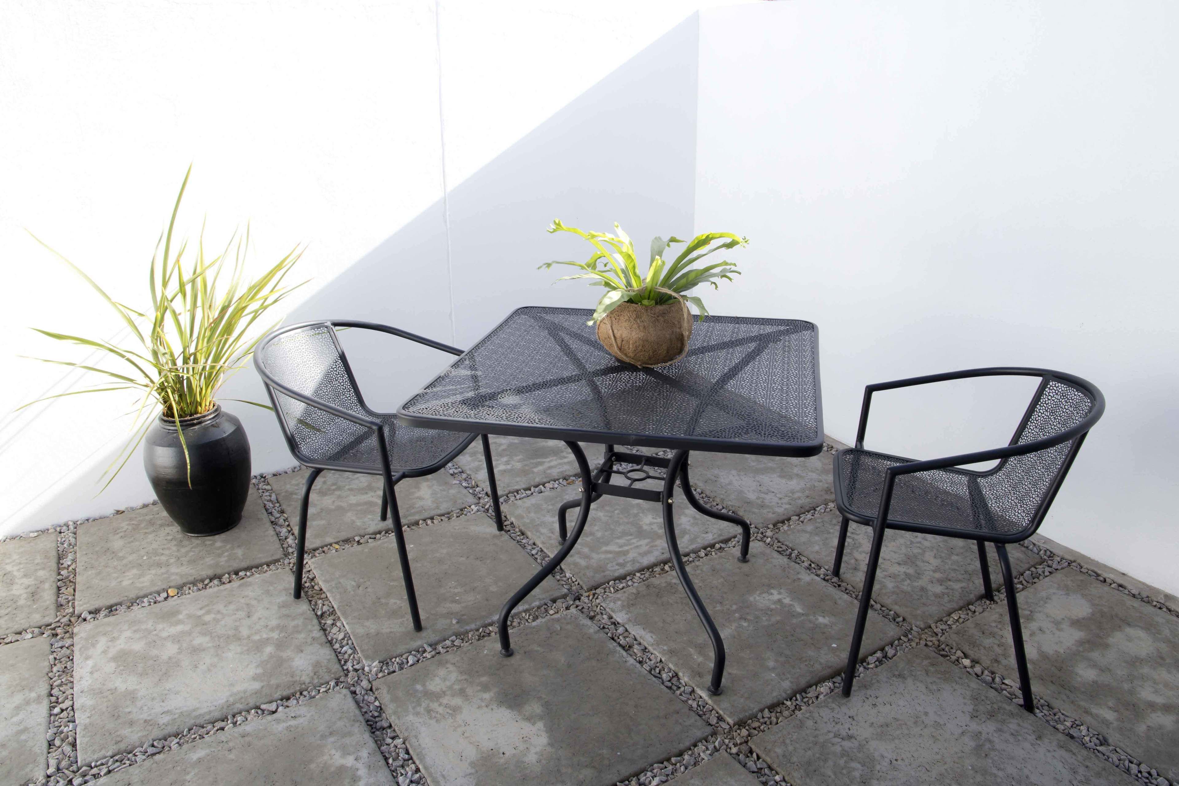 Un patio con una mesa, sillas, una planta en maceta y una pared.