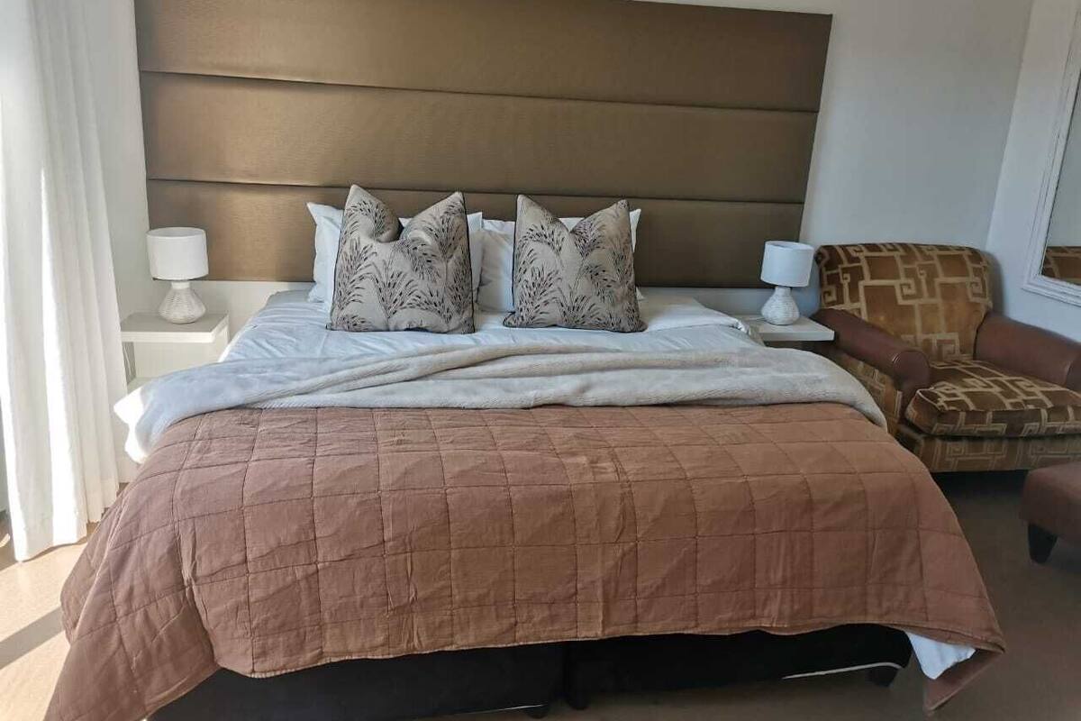 A neatly made bed with a brown quilt, two patterned pillows, and a headboard.