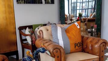 A room with a leather armchair, a peacock sculpture, a patterned rug, and a large mirror reflecting the room.