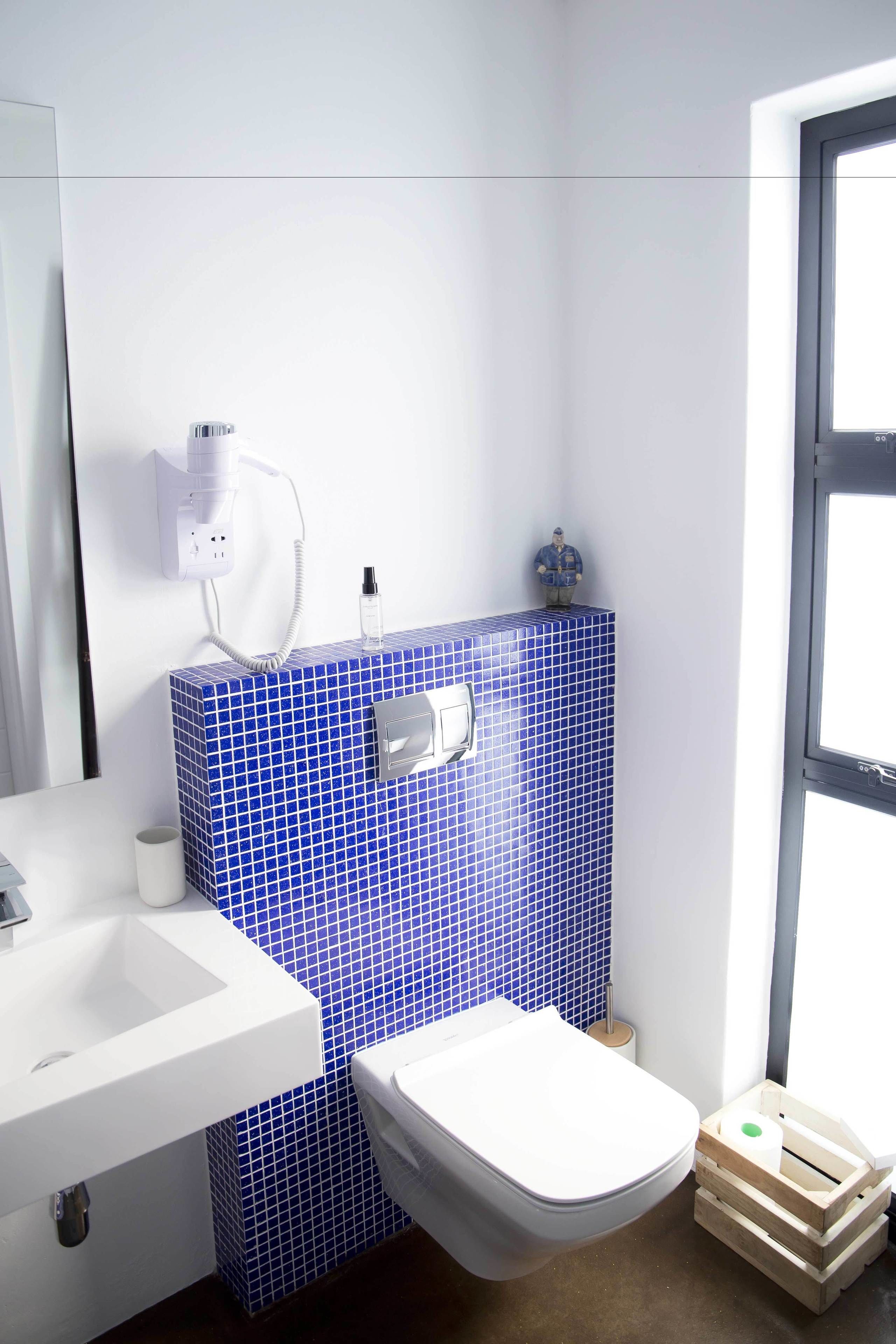 A bathroom with a white sink, a toilet, and a blue-tiled wall.