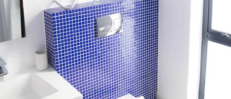 A bathroom with a white sink, a toilet, and a blue-tiled wall.
