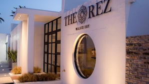 A modern hotel entrance with a sign reading "THE REZ WALVIS BAY". - The Rez Guesthouse (Walvis Bay)