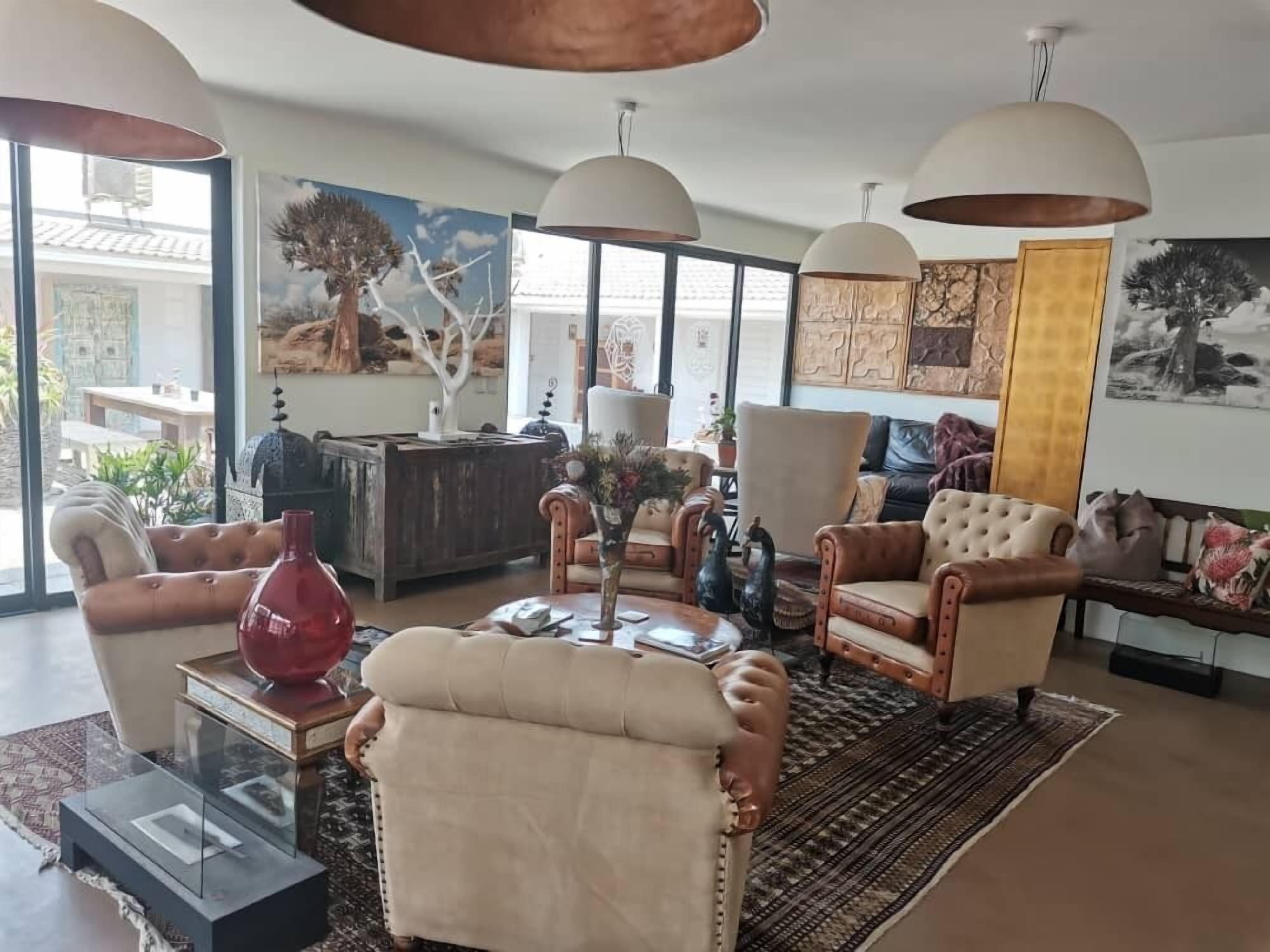 Un salon spacieux avec une grande fenêtre, une table basse en bois et un vase rouge.