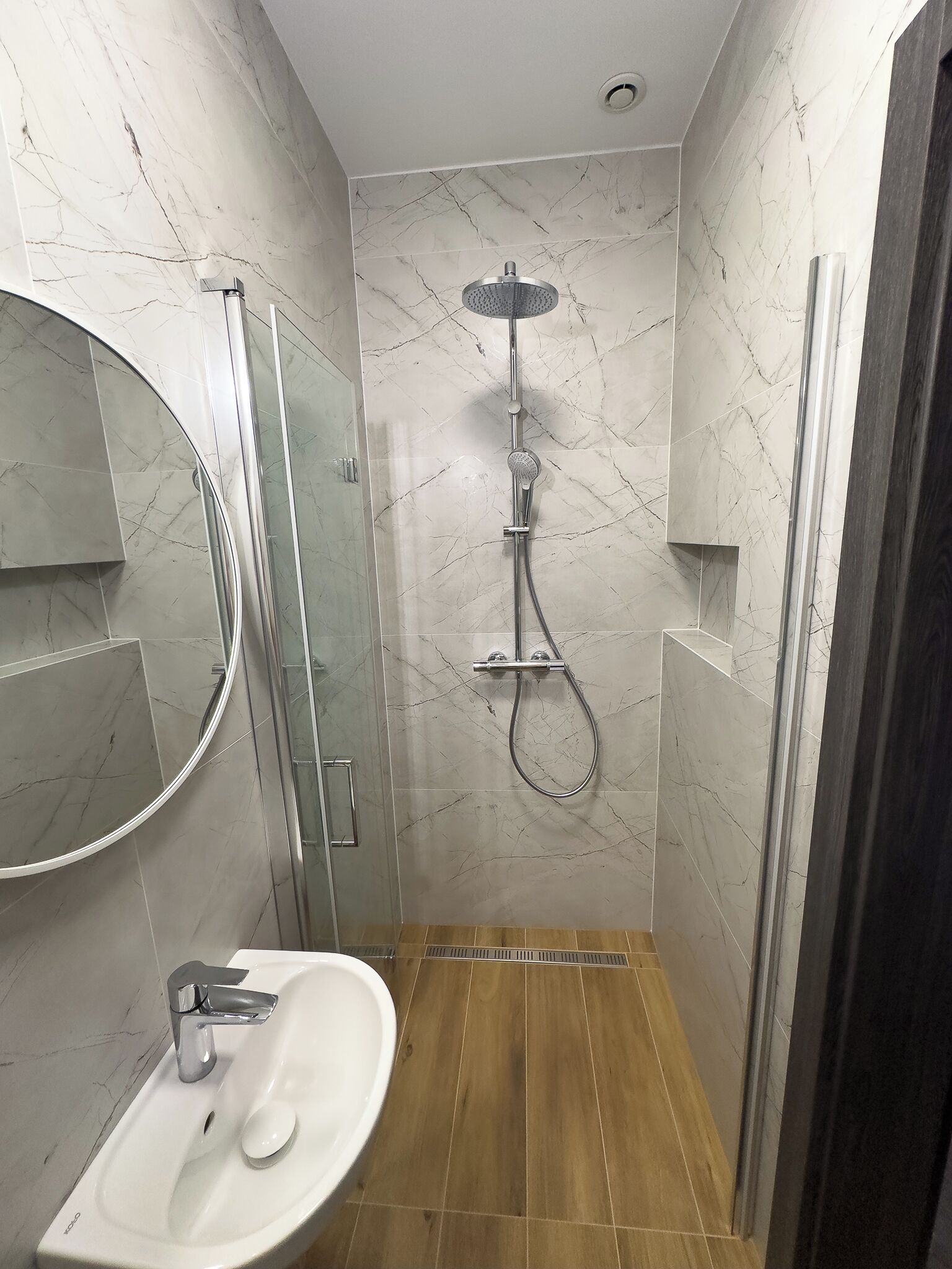 Un baño moderno con ducha, lavabo y espejo.