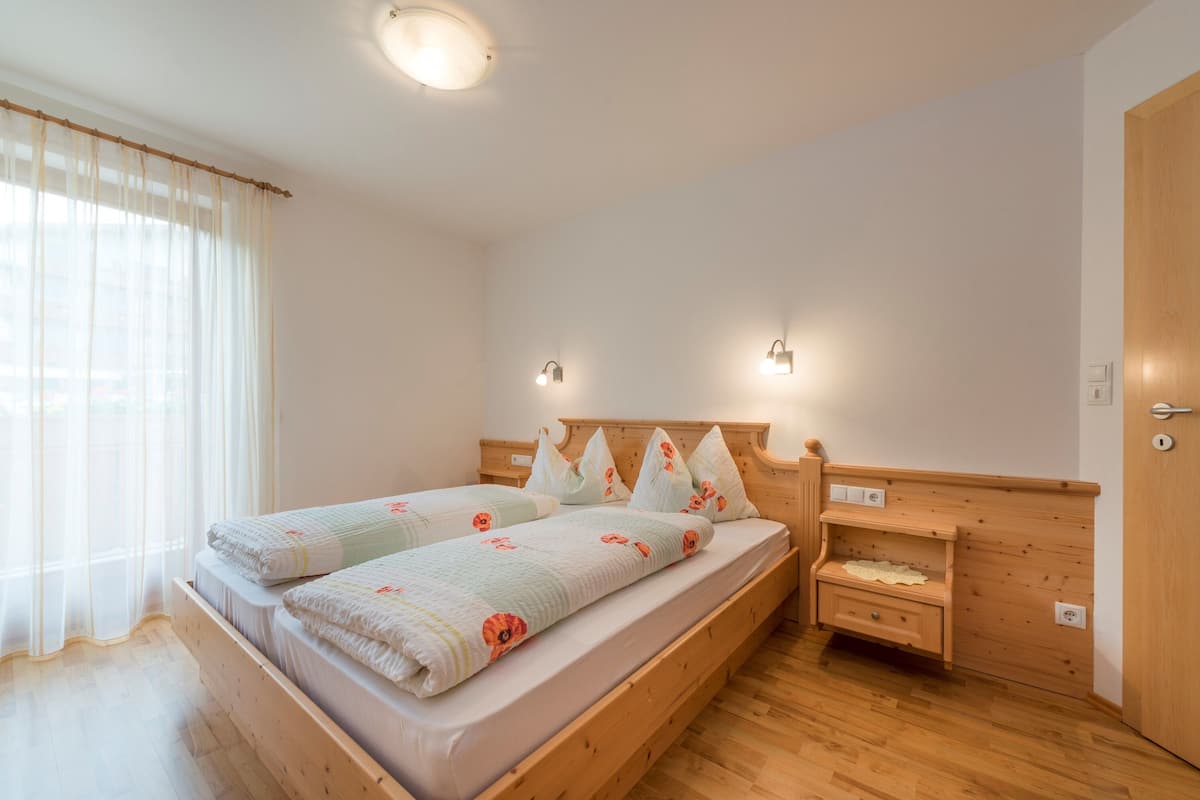 Ein Doppelbett mit floraler Bettwäsche, ein Holzkopfschild, Nachttische und ein Holzschrank.