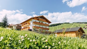 A multi-story building with balconies, surrounded by lush green fields and a clear sky. - Residence Speckerhof (Rio di Pusteria)