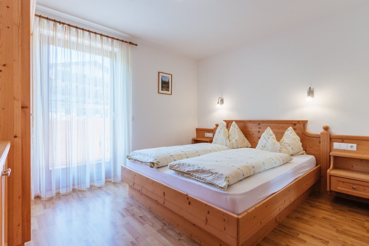 Ein Doppelbett mit Holz-Kopfteil, ein Nachttisch und ein Beistelltisch.