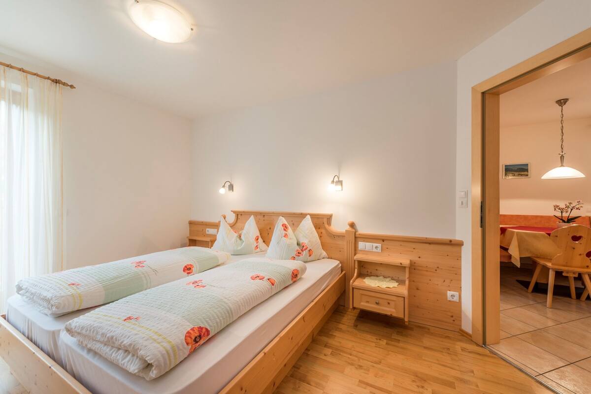 Ein Schlafzimmer mit einem Holzbett, zwei Nachttischen, einem kleinen Holzbeistelltisch und einem kleinen Holzstuhl.