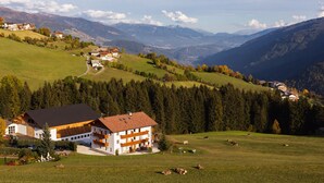 A large building with multiple floors and a sloped roof, surrounded by a green field and trees. - Residence Speckerhof (Rio di Pusteria)