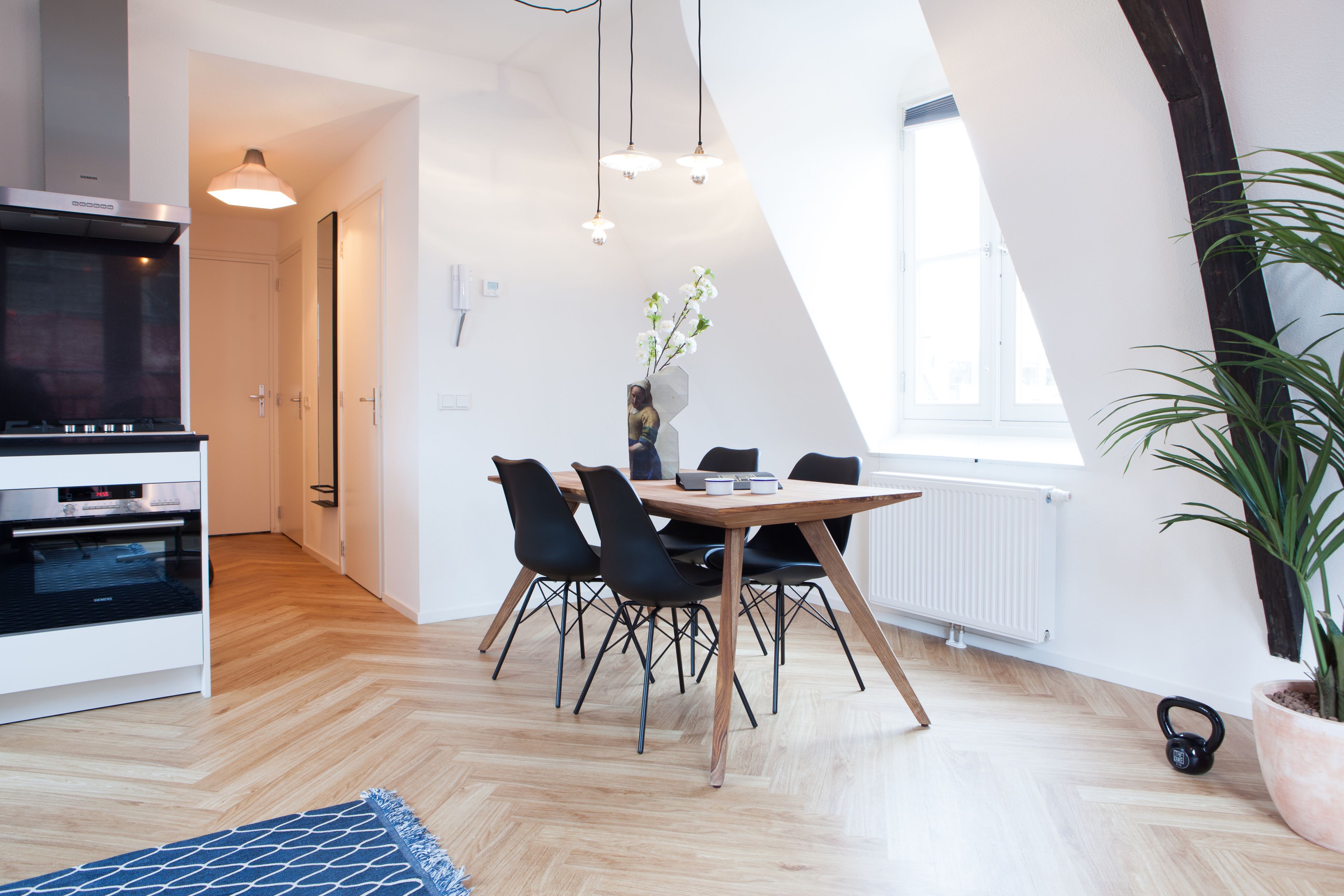 Una cocina moderna con comedor, piso de madera y un amplio ventanal que proporciona luz natural.