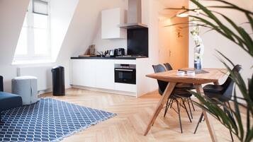 Una cocina moderna con armarios blancos, una estufa negra y un comedor con mesa y sillas de madera.