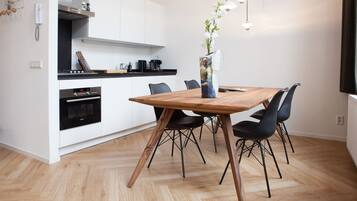 A modern kitchen with white cabinets, a wooden dining table, and black chairs.
