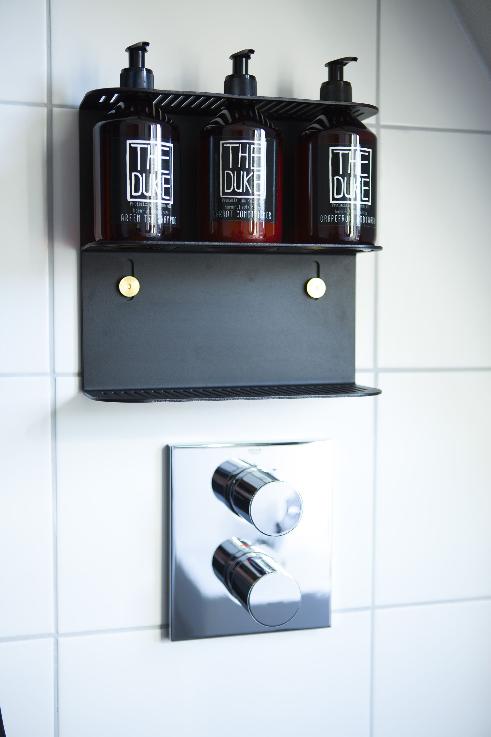 Een badkamerplank met drie Duke toiletartikelen en een moderne kraan.