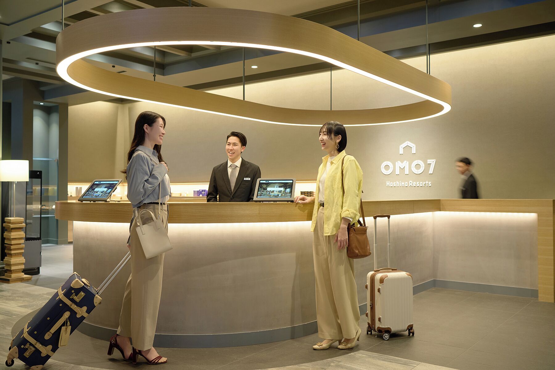 Un comptoir d’accueil au design moderne, doté d’un écran numérique et d’une enseigne indiquant « OMO7 Hashima Resorts ».