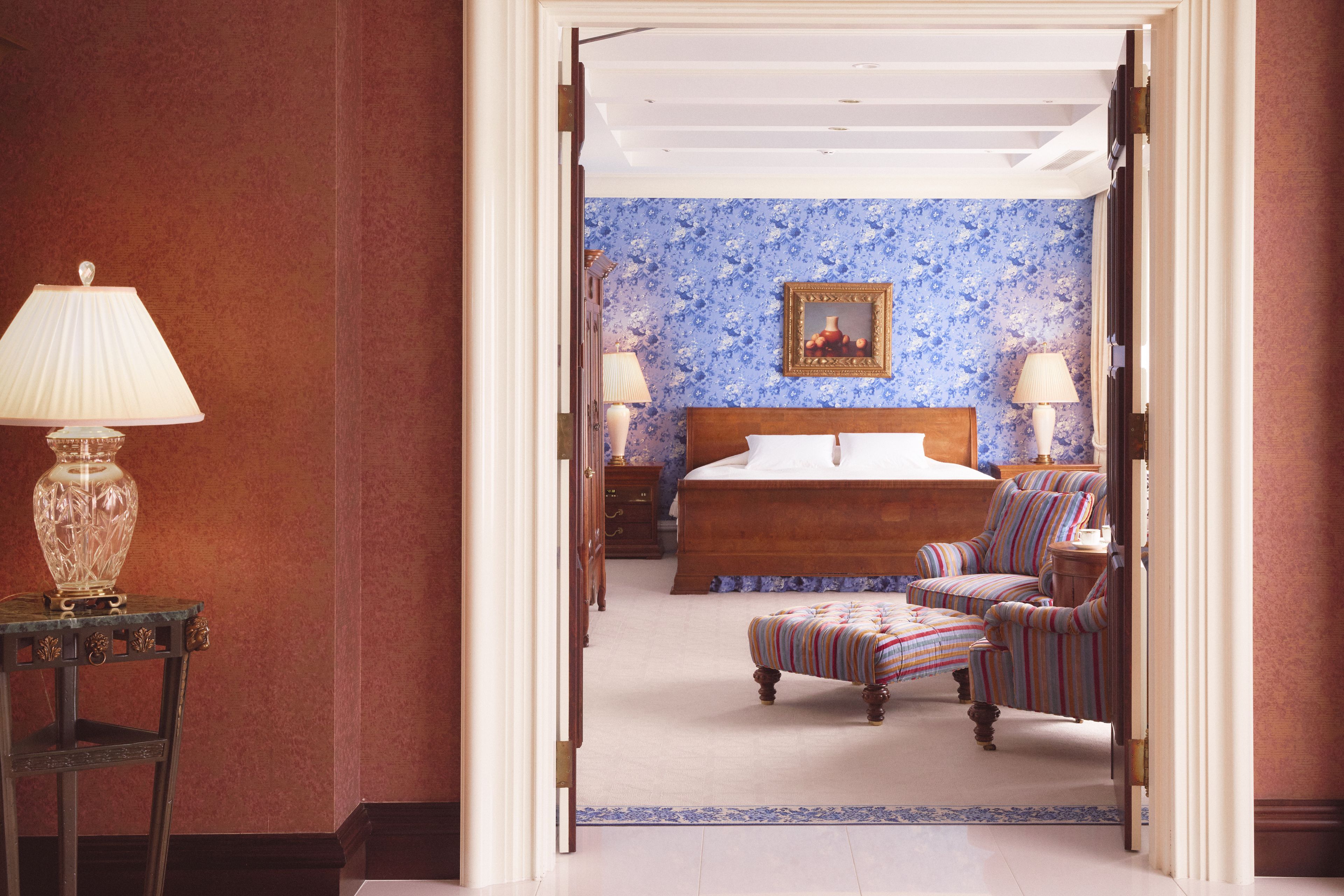 A hotel room with a bed, a nightstand, a lamp, and a chair.
