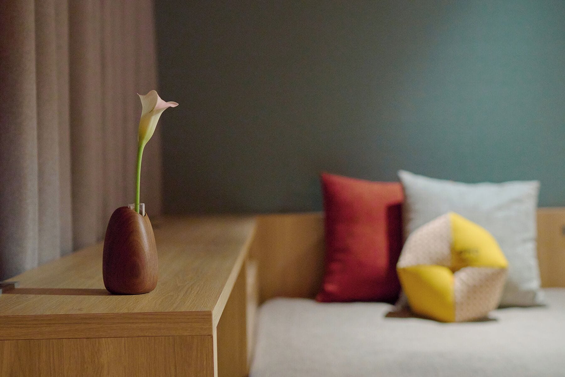 Ein Nachttisch aus Holz mit einer Vase und einer einzelnen Blume.