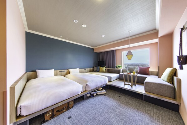Habitación de hotel moderna con una cama grande, un sofá, una mesita y vistas a la ciudad.