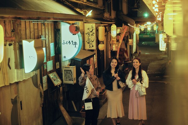 A narrow street with wooden buildings, traditional lanterns, and signs in a foreign language.