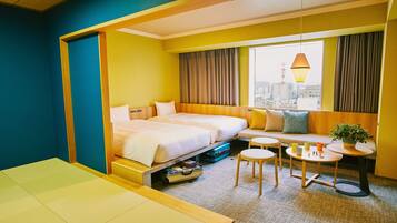 A hotel room with a bed, a sofa, a small table, and a view of the city.