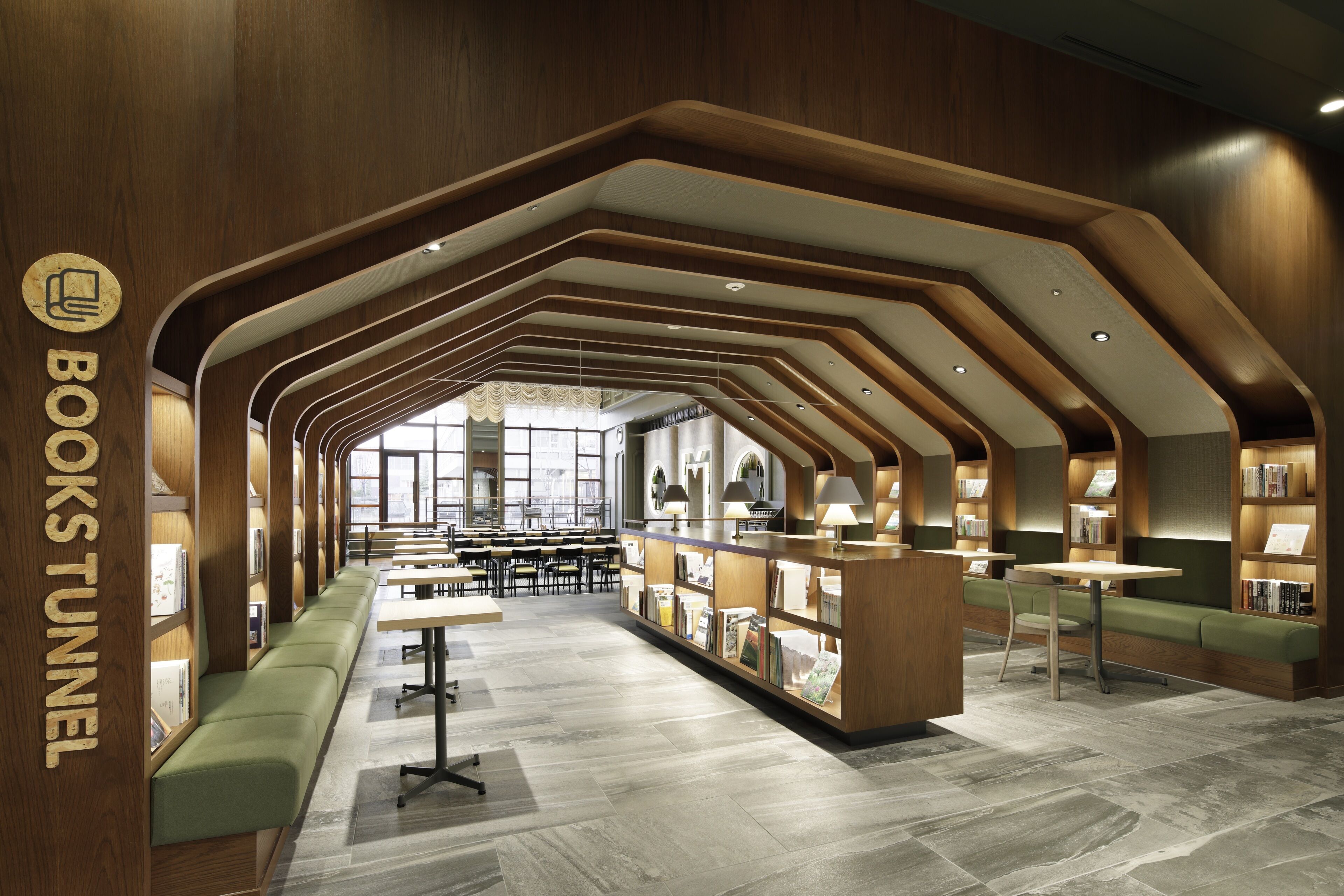 A modern library interior with bookshelves, seating areas, and tables.