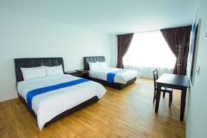 Ein Hotelzimmer mit zwei Betten, Holzboden, einem Tisch und einem Stuhl.