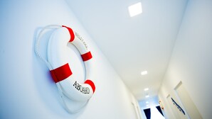 A lifebuoy with "WELCOME" and "ABOARD" text on a white wall in a hallway. - Hard Rock VIP Guest House (Mersing)