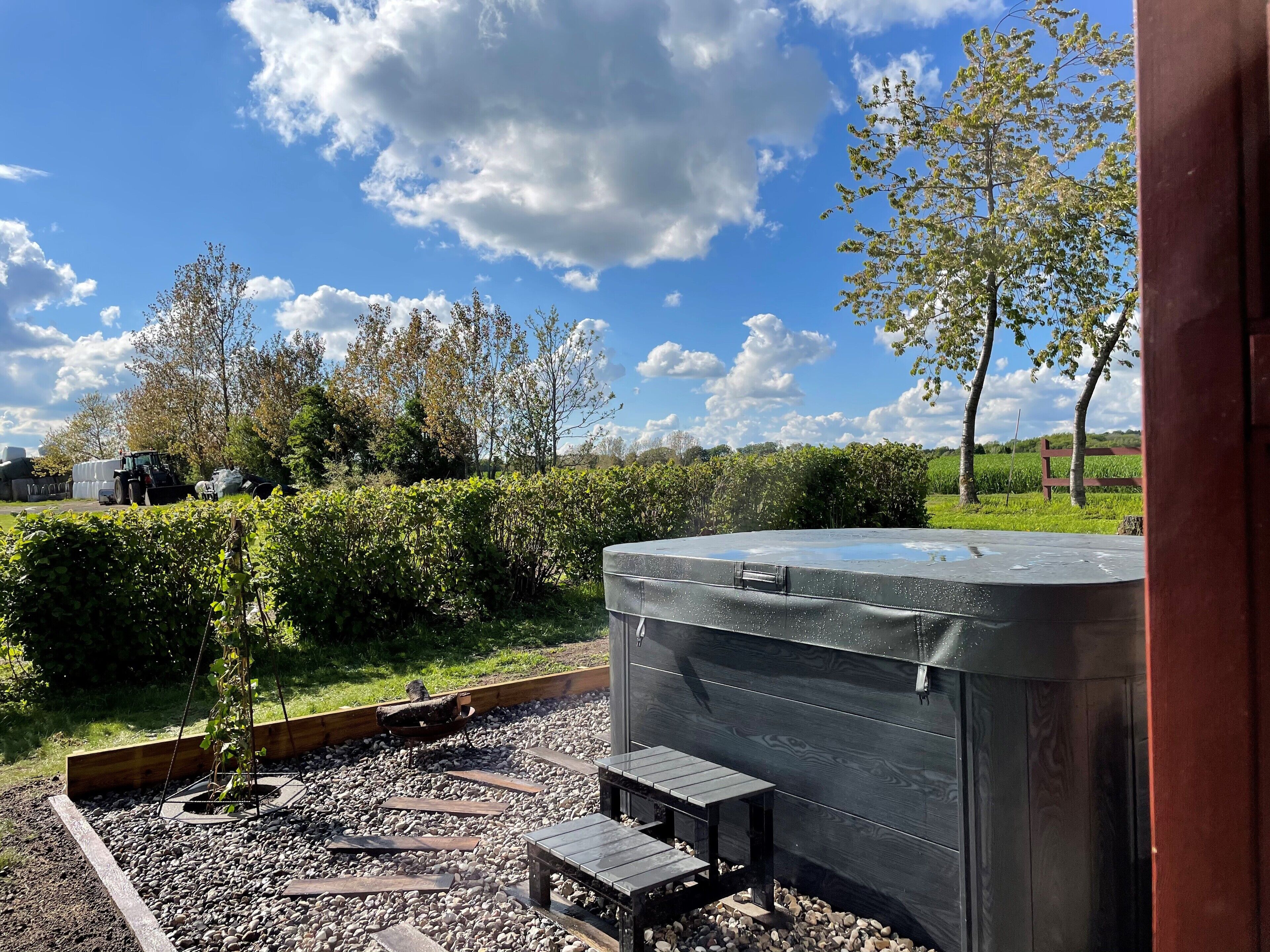 En have med jacuzzi, træbænke og en grussti.