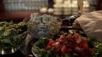 Un tavolo con diversi piatti, tra cui un'insalata, una ciotola di salsa gorgonzola e un piatto di pomodori a cubetti.