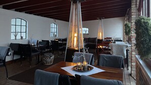 A spacious indoor dining area with high ceilings and large windows, featuring modern furniture and decorative lighting. - Husargårdens Bed & Breakfast (Sjobo)