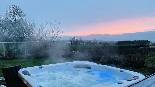 A hot tub with a view of a sunset and a rural landscape. - Husargårdens Bed & Breakfast (Sjobo)