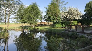 A serene pond surrounded by trees and a wooden bridge. - Husargårdens Bed & Breakfast (Sjobo)