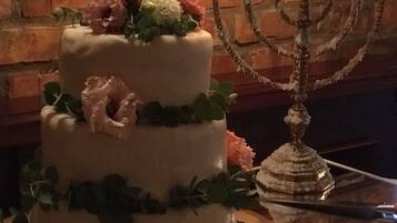 En tårta i tre våningar, dekorerad med blommor, och en tänd menorah bredvid.