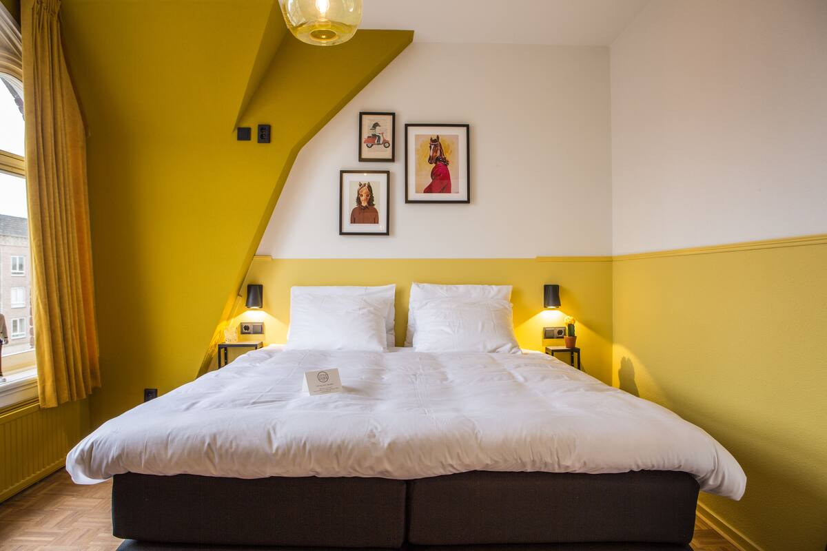 A hotel room with a large bed, two bedside tables with lamps, and three framed pictures on the wall.