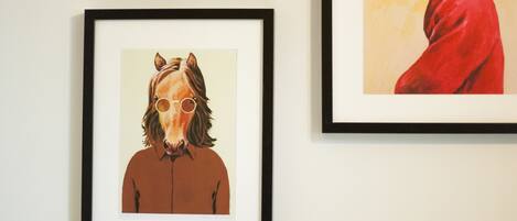 Three framed artworks on a wall above a bed.