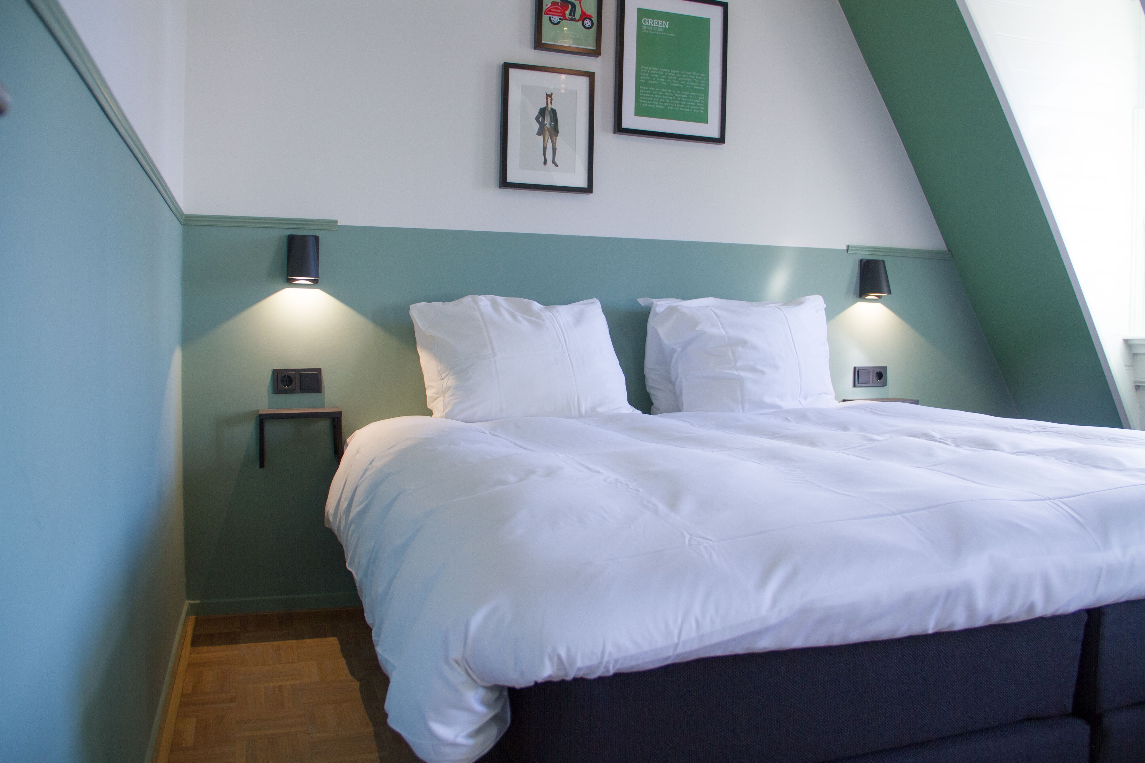 A neatly made bed with white bedding, two bedside tables with lamps, and a framed picture on the wall.