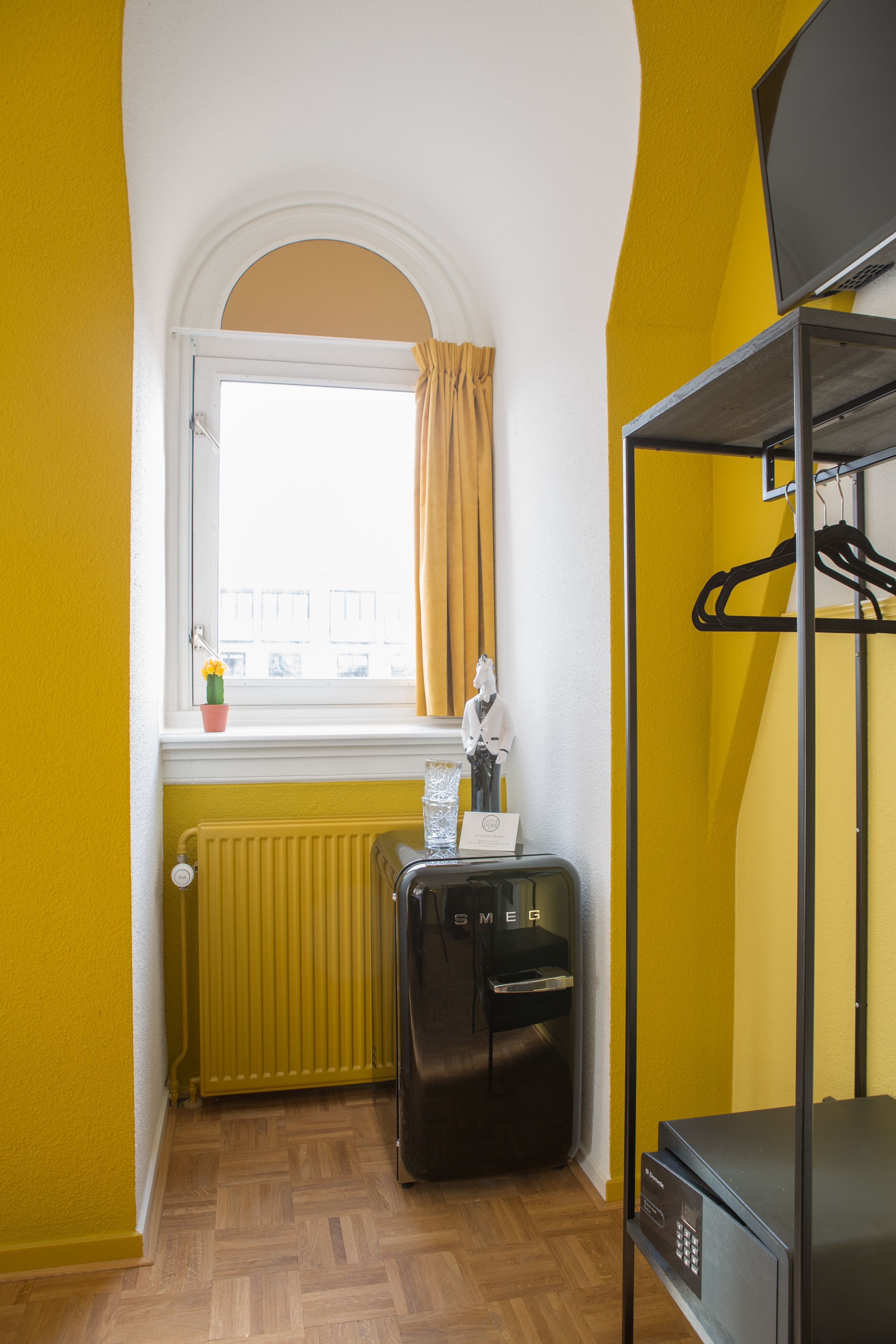 A compact room with a window, radiator, and a black refrigerator.