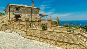 Una casa in pietra con tetto in tegole, una scala in pietra e vista sul mare.