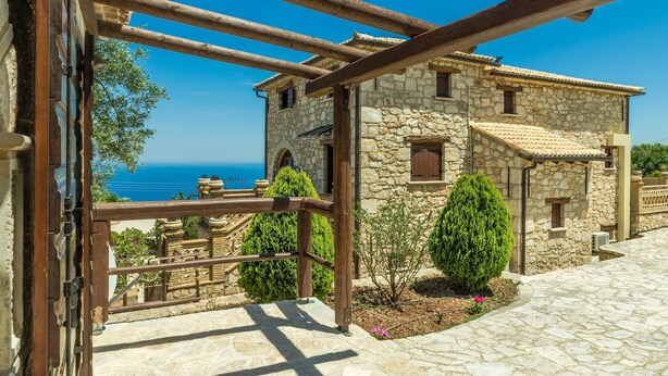 Un edificio in pietra con una scala di pietra che conduce a una terrazza con vista sul mare.