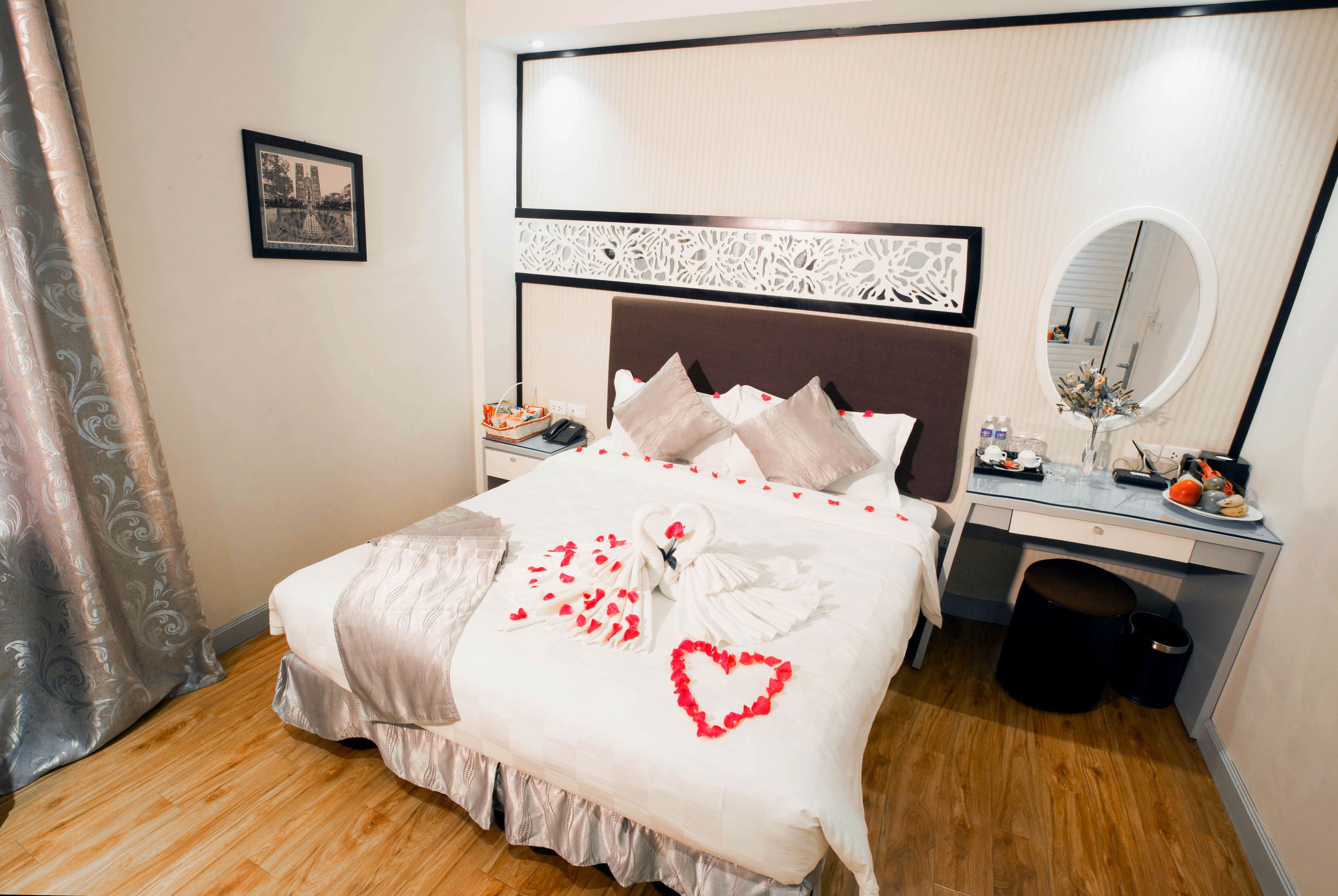 A neatly made bed with a heart-shaped decoration and a towel arranged in the shape of a heart.