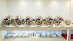 A buffet setup with multiple serving stations, each with a dome cover and a red napkin.