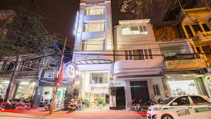 A multi-story hotel with a prominent Riverside sign, outdoor seating, and a parking area with motorcycles.