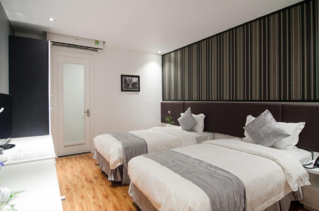 Ein Hotelzimmer mit zwei Betten, einem Schreibtisch und einem großen Fenster.