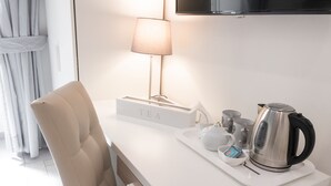 Moderni keittiö, jossa on valkoinen työtaso, teekyltti, vedenkeitin ja lamppu.