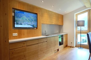 A modern kitchen with wooden cabinetry, a built-in oven, and a large window providing natural light. - Apart Auhof (See)
