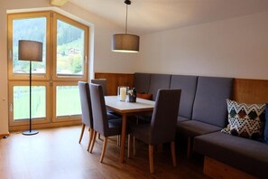Un comedor con una mesa, sillas y un sofá. Se aprecia una ventana con vistas a zonas verdes.