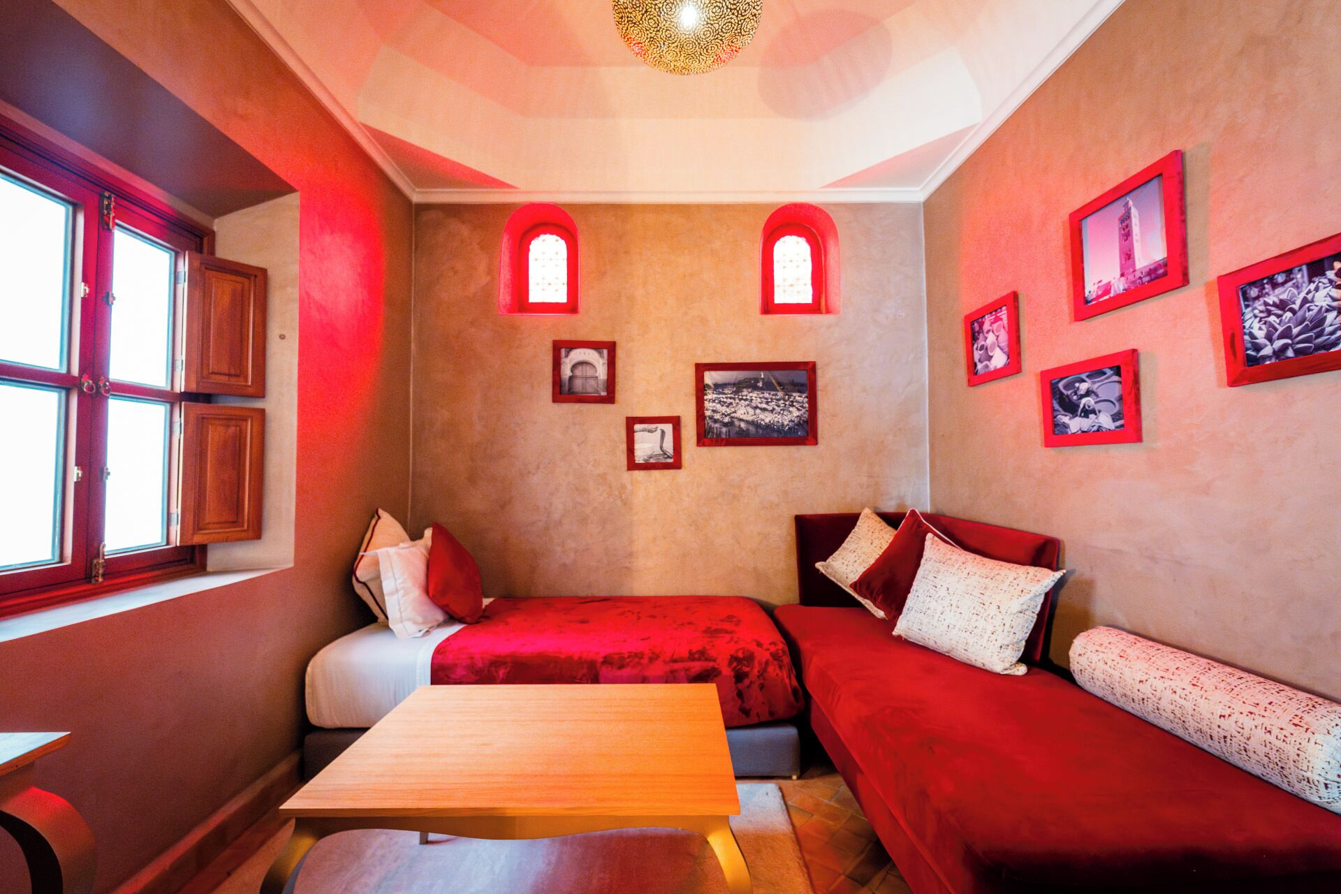 A cozy room with two beds, a wooden table, and red walls.