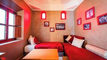 A cozy room with two beds, a wooden table, and red walls.