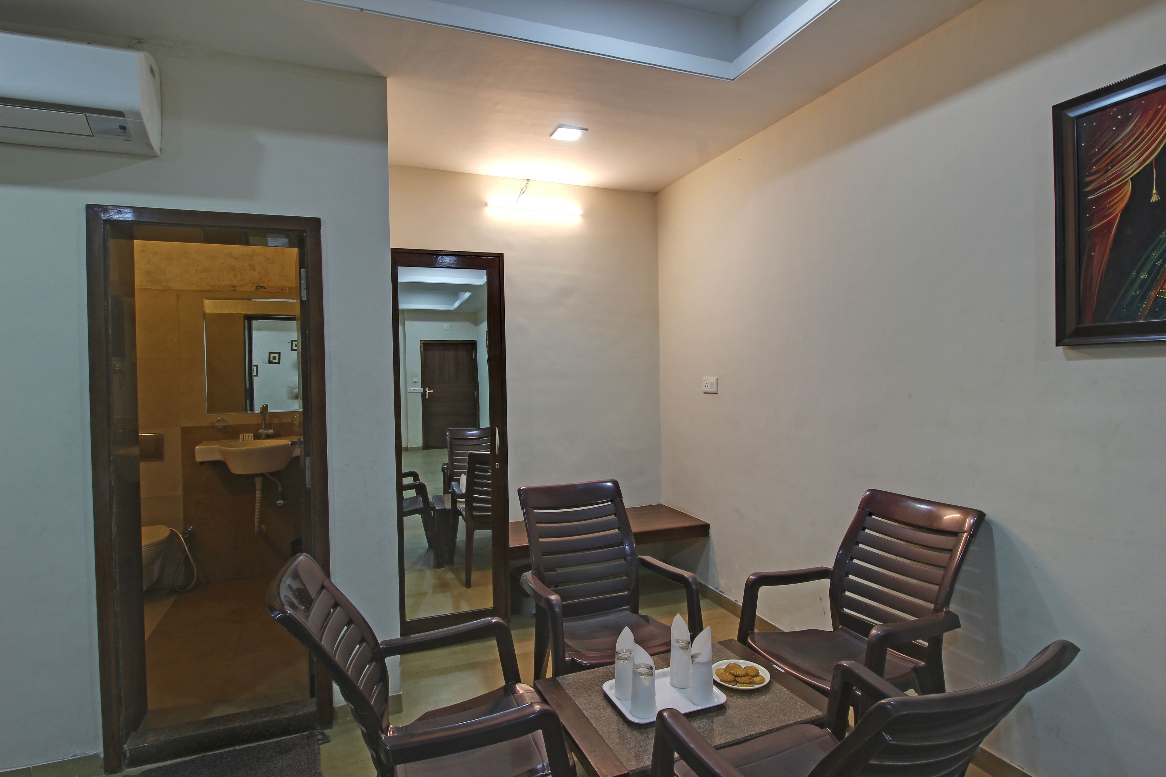 Un comedor con una mesa, cuatro sillas y un espejo que refleja la habitación.