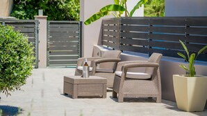 Un espace extérieur aménagé avec des meubles en osier et un pot de fleurs.