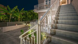 Un bâtiment moderne doté d’un escalier menant à un balcon, le tout entouré d’une végétation luxuriante.